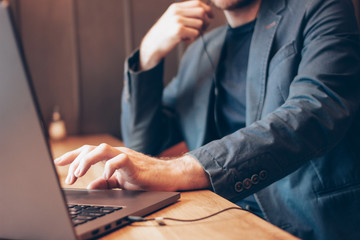 The man in blue suit with headphones working on a laptop in cafe