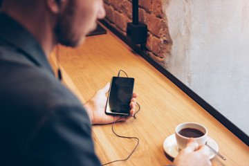 The man using mobile phone, sitting with coffee at cafe