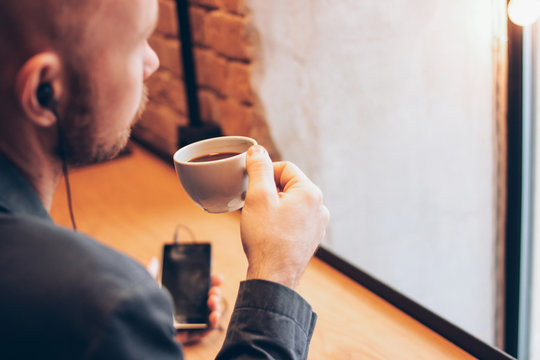 The man using mobile phone, sitting with coffee at cafe