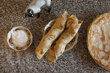 Pancakes with sour cream on kithcen table and a cat porcelain statue