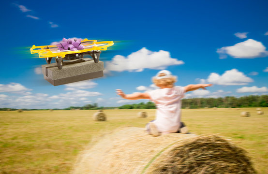 Funny photo manipulation of drone delivering gift box in rural area countryside, blurred field with hay balls and child hands reached out and doing fly move, sunny day. Drone delivery concept.