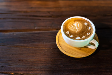 Latte art coffee cup on wooden table, Dark background, Vertical