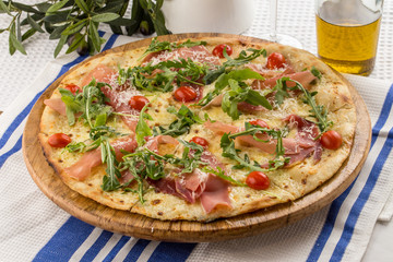 Pizza with prosciutto and arugula salad rocket on textile napkin
