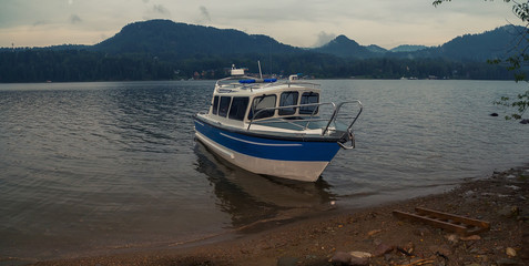 Fototapeta premium summer landscape on a mountain lake. fog over forest. ships and boats floating near the shore on the water