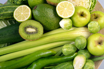 Green vegetables on wooden plate on white background