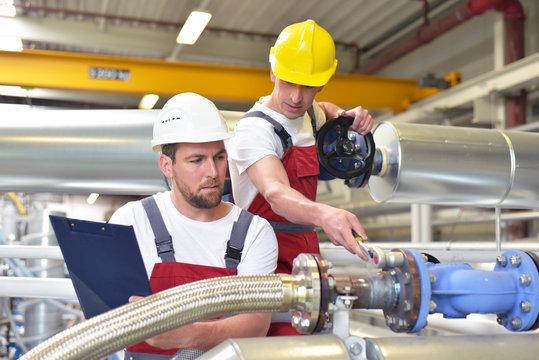Gruppe Monteure bei der Instandhaltung in der Industrie // Mechanics repair a machine in a modern industrial plant - profession and teamwork