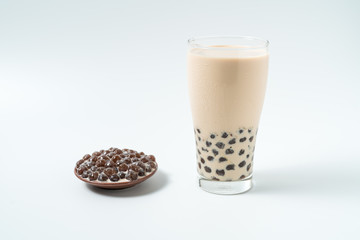 A glass cup of pearl milk tea (also called bubble tea) and a plate of tapioca ball on white background. Pearl milk tea is the most representative drink in Taiwan. Taiwan food . With copy space.