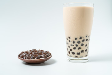 A glass cup of pearl milk tea (also called bubble tea) and a plate of tapioca ball on white background. Pearl milk tea is the most representative drink in Taiwan. Taiwan food . With copy space.