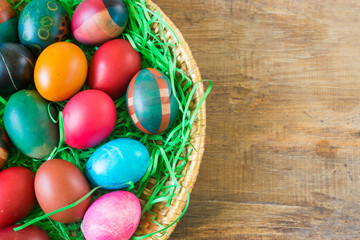 Colorful Easter eggs in basket on old wooden background