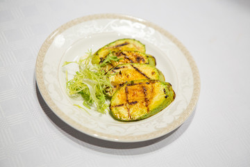 delicious fried zucchini grilled beautifully served on a platter in the restaurant,.fried zucchini in oil on a plate close-up, zucchini with toasted crust and salad on a dish