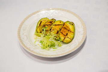 .delicious fried zucchini grilled beautifully served on a platter in the restaurant,.fried zucchini in oil on a plate close-up, zucchini with toasted crust and salad on a dish