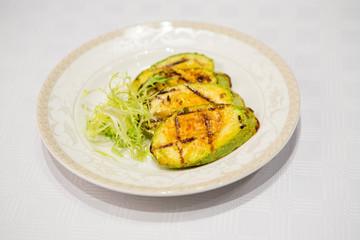 delicious fried zucchini grilled beautifully served on a platter in the restaurant,.fried zucchini in oil on a plate close-up, zucchini with toasted crust and salad on a dish