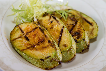 delicious fried zucchini grilled beautifully served on a platter in the restaurant,.fried zucchini in oil on a plate close-up, zucchini with toasted crust and salad on a dish