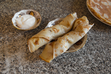 Pancakes with sour cream on kithcen table and a cat porcelain statue