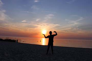 black silhouette of a man against the blue sea and sunset sky