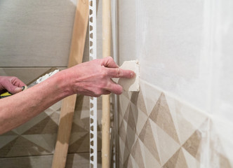 Worker with a rubber spatula fill the seams with a solution. Finishing works, blurred focus. The technology of laying tile.