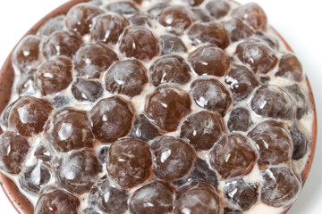A glass cup of pearl milk tea (also called bubble tea) and a plate of tapioca ball on white background. Pearl milk tea is the most representative drink in Taiwan. Taiwan food . With copy space.