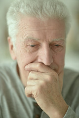 Close-up portrait of sad senior man at home