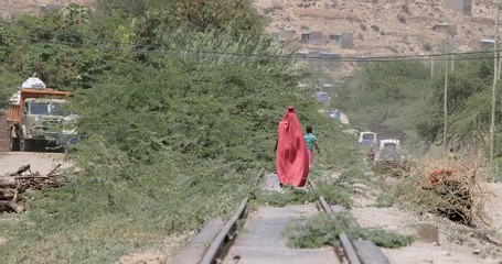 Somali woman walking down railroad track near the Ethiopia, Somalia, Djibouti border.