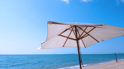 Fototapeta na wymiar White fabric color texture beach umbrella and brown wood tripod with white cloud and clear blue sky summer sunlight day in low angle view camera for travel asia Thailand Pattaya.