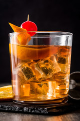 Old fashioned cocktail with orange and cherry on wooden table
