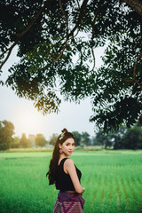Obraz premium Beautiful Asian woman in local dress standing and enjoy natural on bamboo bridge in rice field