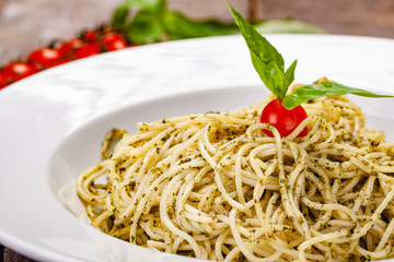 Italian pasta spaghetti with homemade pesto sauce on white plate. Close up
