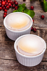 Souffle with cranberries in white ramekin on wooden rustic table. Close up