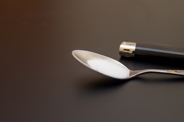 spoon with drugs for heroin cooking on dark table. Drug addiction concept