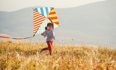 happy child girl running with kite at sunset outdoors.