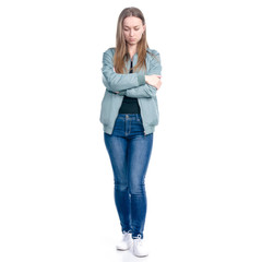 Woman in jeans and green jacket standing offended on white background isolation