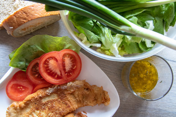 Fried hake fish fillet pieces on plate and salad