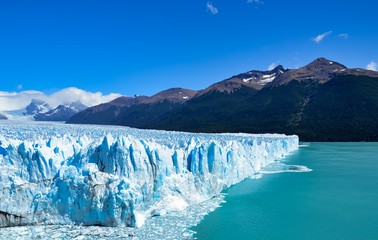 View of a branch of the Perito Moreno progressing into the water of the lake, with mountains in the...