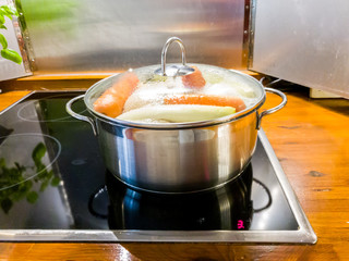 Chicken soup cooking in a pot on ceramic glas cooktop