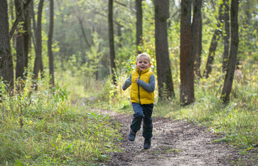 Young boy runs along a forest path