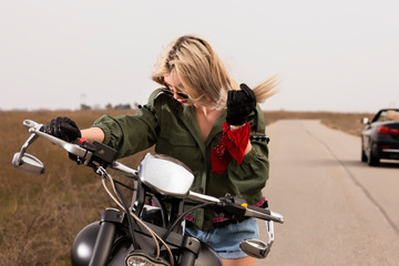 Fototapeta na wymiar A beautiful young woman sitting on a black and chrome motorbike