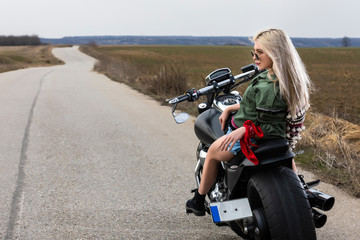 Fototapeta na wymiar A beautiful young woman sitting on a black and chrome motorbike