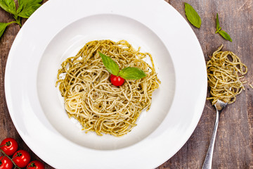 Italian pasta spaghetti with homemade pesto sauce on white plate. Top view. Close up