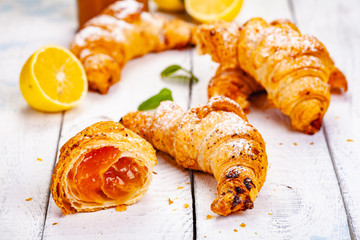 Croissants with lemon jam on white wooden background. Close up