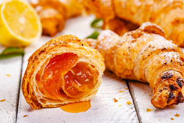 Croissants with lemon jam on white wooden background. Close up