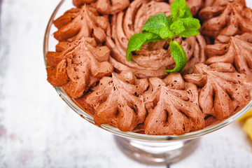 Homemade chocolate mousse in portion glass on wooden background. Close up