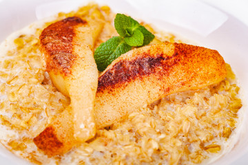 Oatmeal porridge with pear in white plate. Close up
