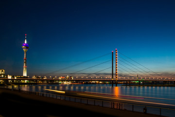 A picture of the center of Dusseldorf in Germany during the evening. The sun went down and only blue sky is above the city. 