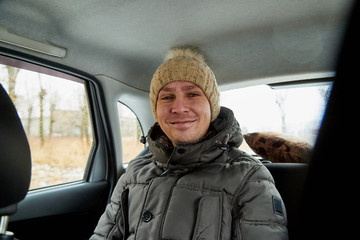 Funny man in warm clothes and women's hat in the car