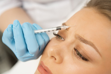 Close up of a professional cosmetologist making botox injection in the face of her female client. Beautiful woman getting facial treatment at the clinic plastic surgery fillers cosmetology syringe 