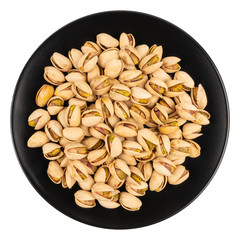 Pistachios in a black plate isolated on white background.