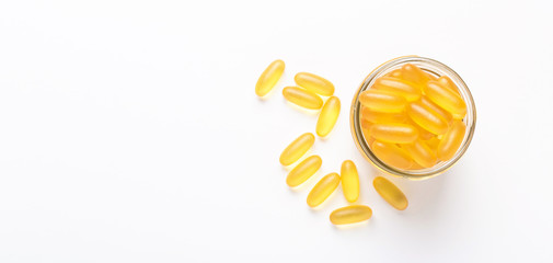Omega 3 capsules in glass jar on white background Fish oil Yellow softgels Vitamin D, E, A...