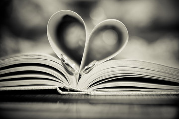 Two wedding rings placed in a book to make a heart shape