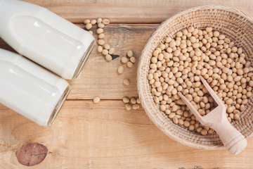 Bottle of soy milk and soy beans on wood background.
