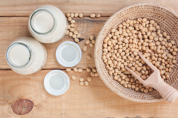 Bottle of soy milk and soy beans on wood background.